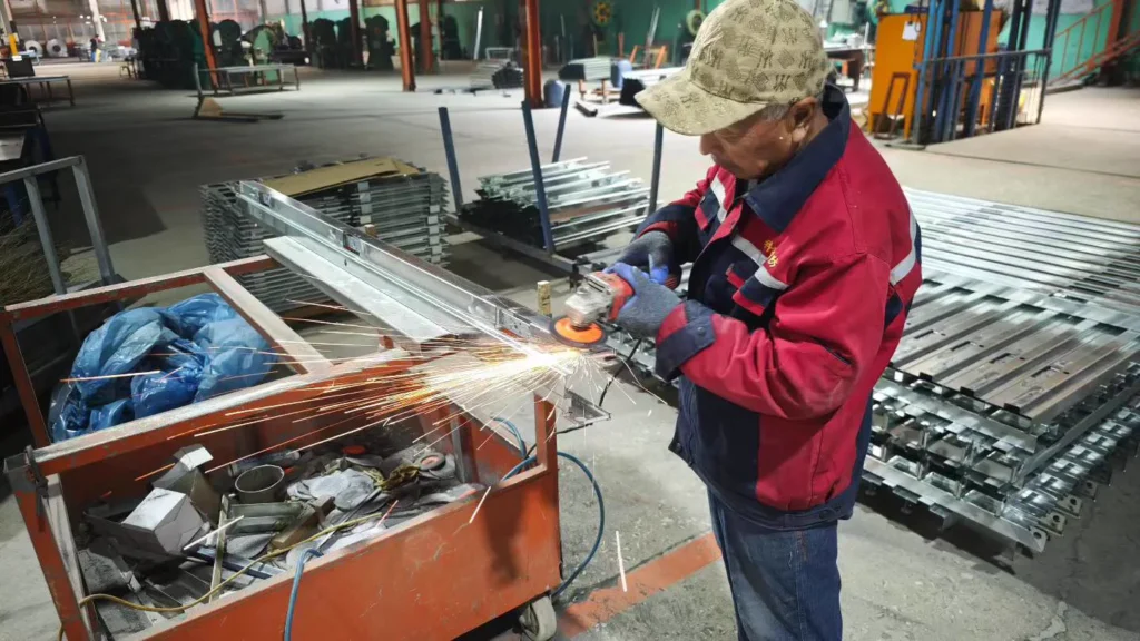 Worker performing fabrication detail on commercial door components