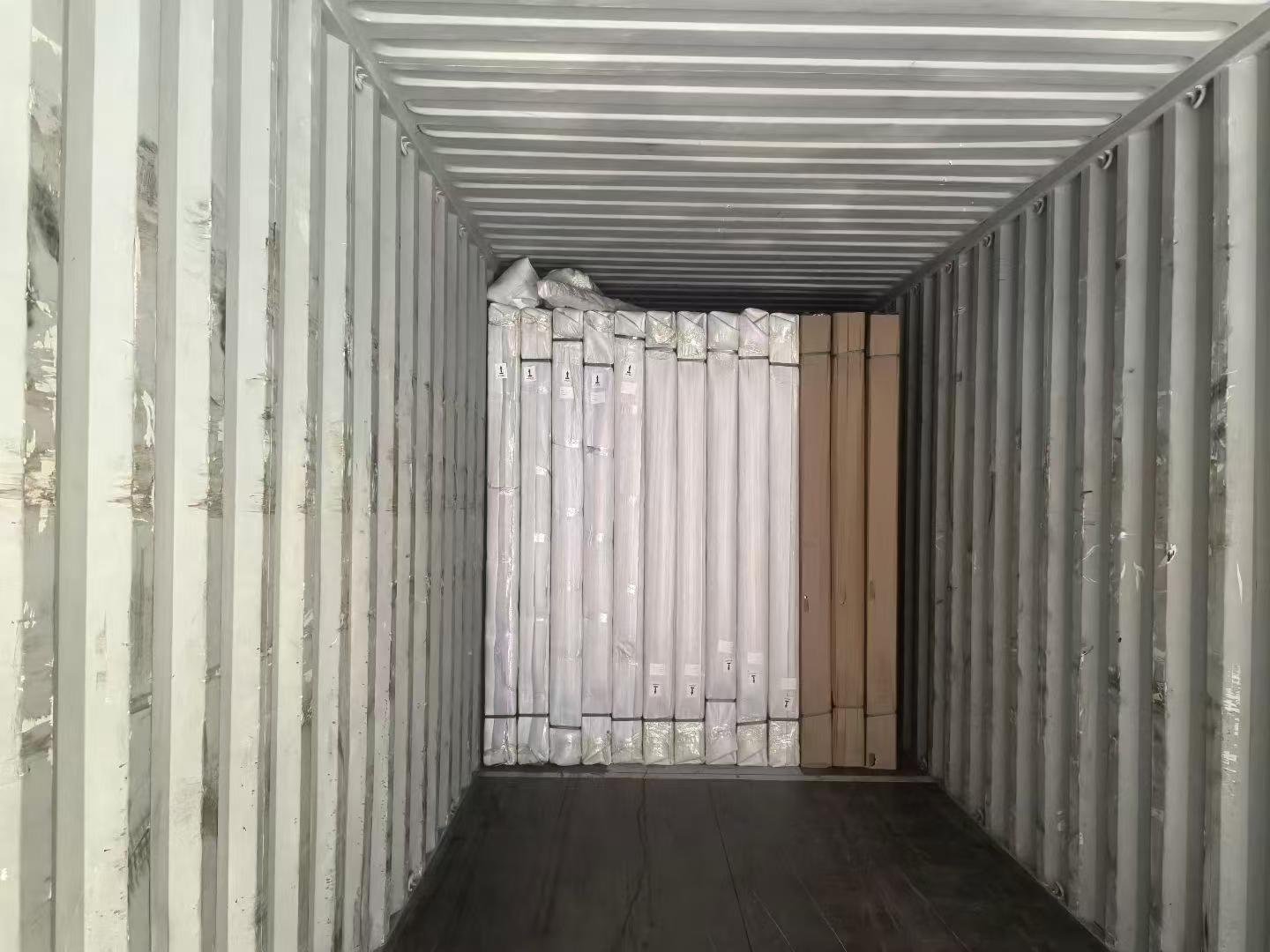 Wrapped UL fire-door packages and boxed components secured at the end of an export container for Canada