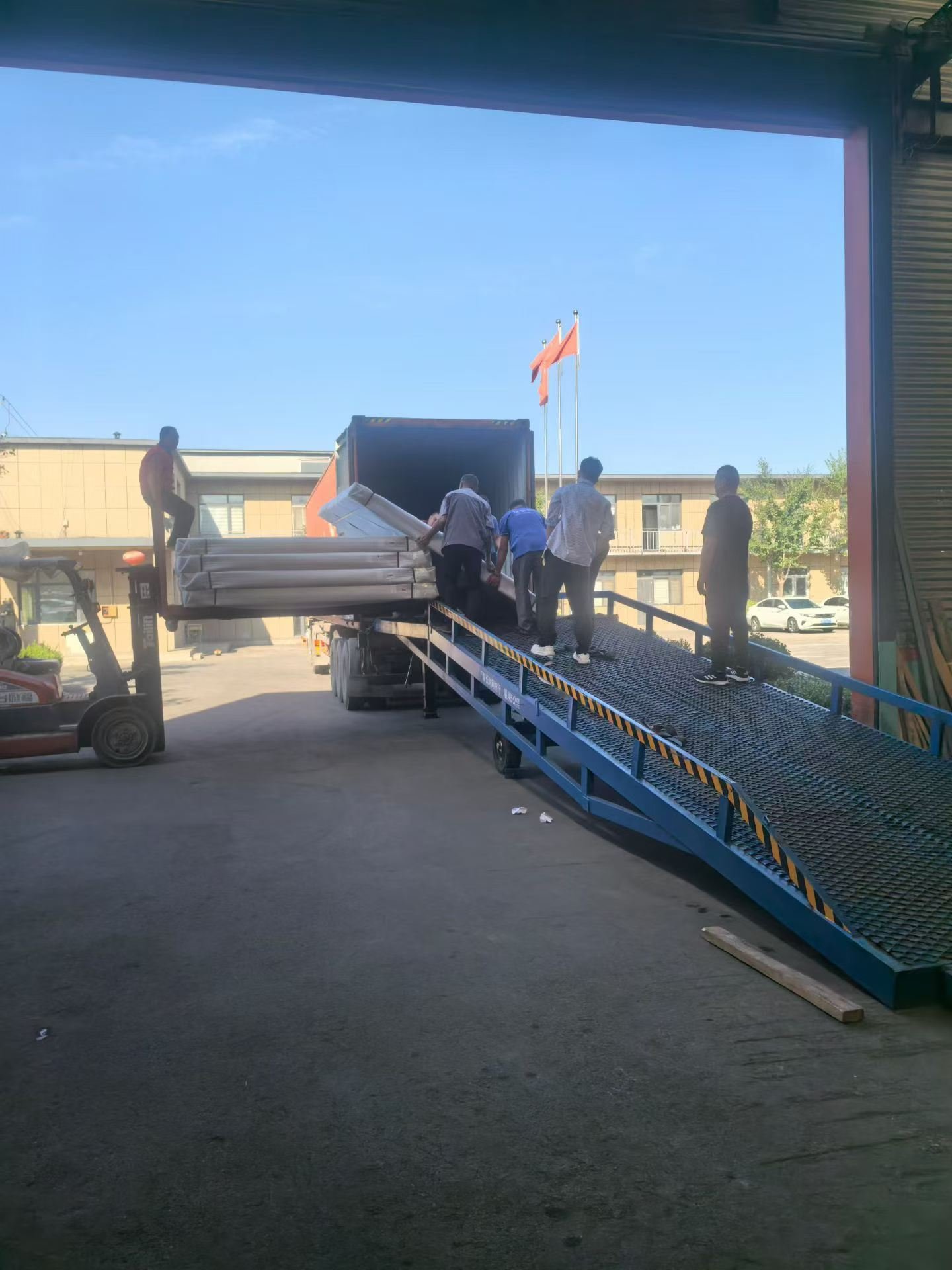 Workers guiding protected UL fire-door packages up a loading ramp into an export container for Canada